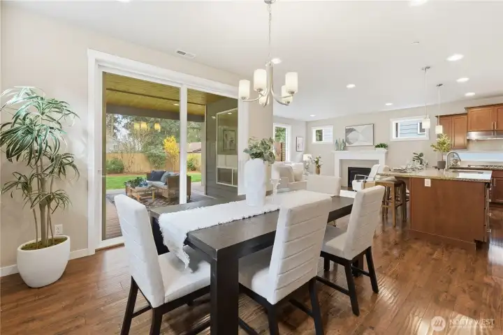 A bright dining nook with a lovely outlook through the slider doors to the covered patio and peaceful garden beyond