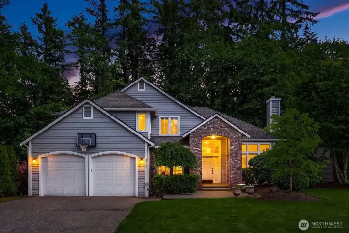 A warm twilight glow highlights the elegant exterior of this Murray Franklyn home, featuring classic craftsman details, lush mature landscaping, and an oversized 2-car garage in Klahanie's coveted Ashley Park community.