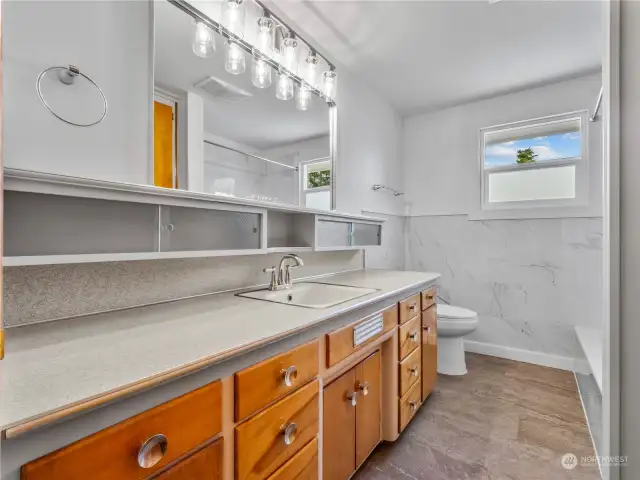 The bathroom retains the beautiful original cabinets with updated tile, flooring, and lights