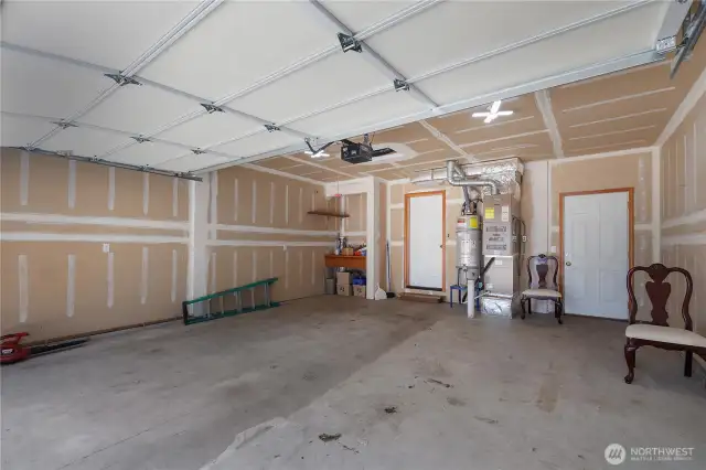 Garage with workbench in the corner. Door on left accesses the home, door on right goes out to side/back yard.