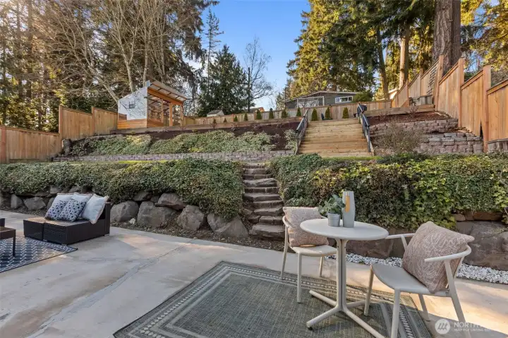 Fully fenced outdoor sanctuary with easy-care landscaping, an expansive levelled terraced backyard, a large patio for entertaining, a gardener's greenhouse, and a storage shed.