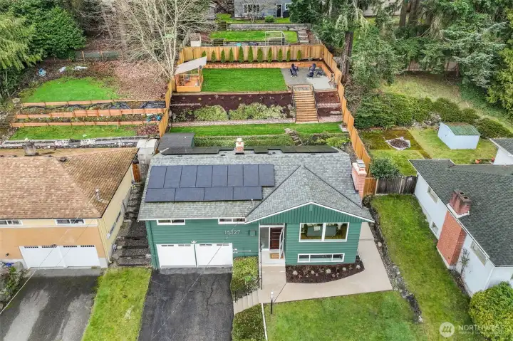 Fully fenced outdoor sanctuary with easy-care landscaping, an expansive levelled terraced backyard, a large patio for entertaining, a gardener's greenhouse, and a storage shed.