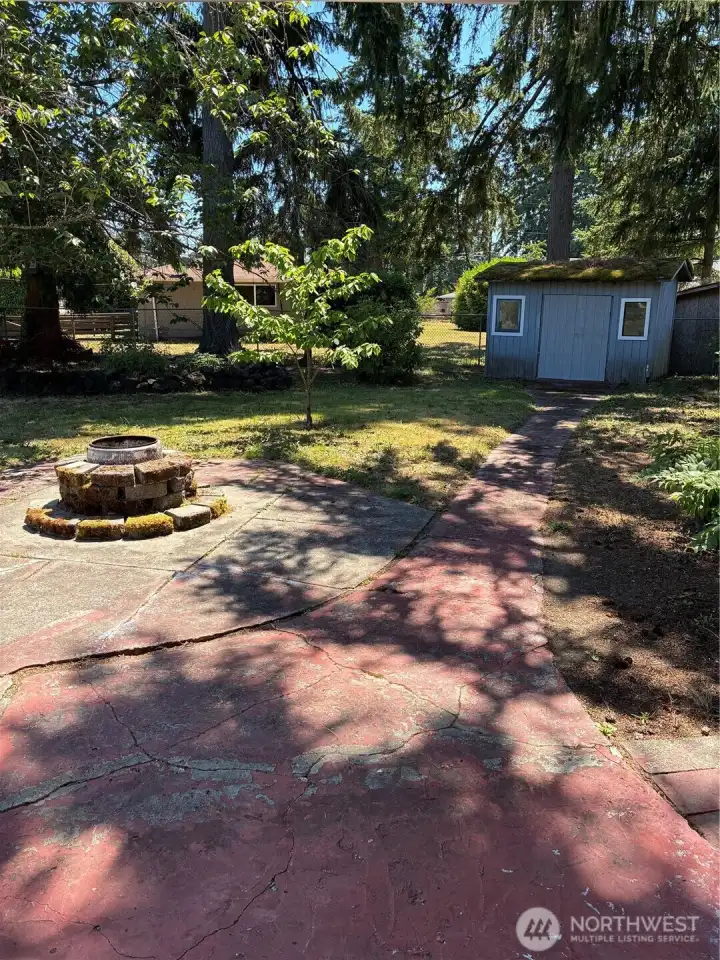 Backyard features fire pit, cherry tree, sheds, and spacious patio
