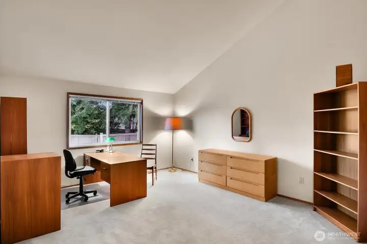 Oversized primary bedroom enjoys a high, vaulted ceiling and a deep walk-in closet in its own separate “wing”