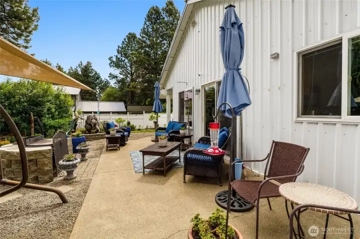 Backyard patio with seating area, umbrellas, and outdoor living space adacent to home