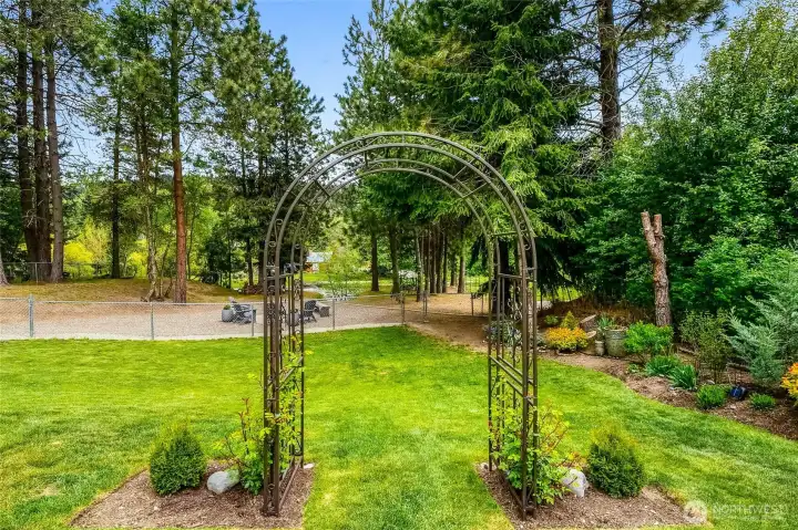 Landscaped yard with decorative garden arch and open lawn space