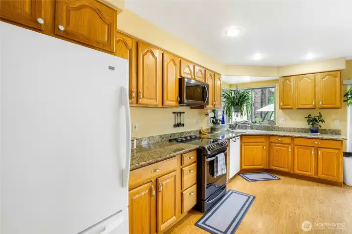 Kitchen with wood cabinetry, solid surface counters, and appliances