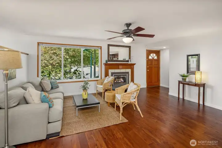 Rich wood flooring, a gas fireplace insert, and an open connection to the kitchen make this living space comfortable and easy to enjoy.