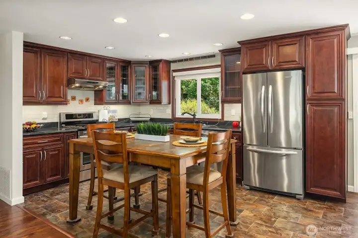Cherry cabinetry, glass-front display cabinets, generous storage, and thoughtful custom details give this kitchen both character and functionality.