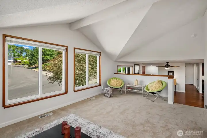 Natural light and elevated neighborhood views enhance this adaptable upper-level space beneath dramatic vaulted ceilings.