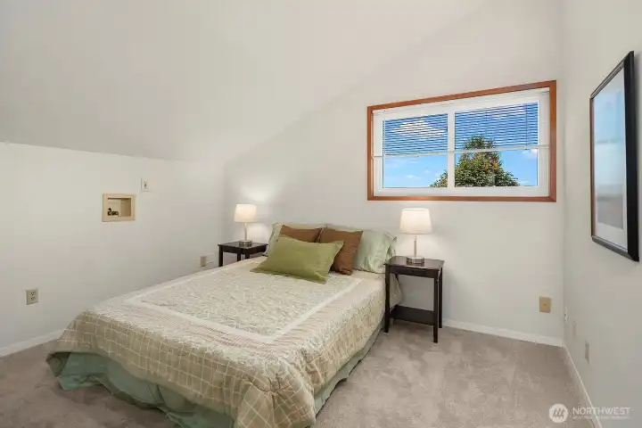 Bright and peaceful, this bedroom offers a vaulted ceiling, generous floor space, and an elevated outlook through its windows.
