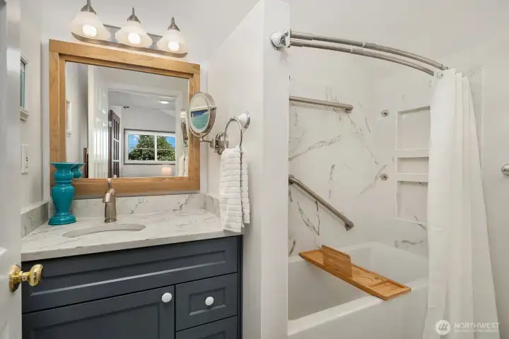 One of two beautifully renovated bathrooms, this one features a soaking tub with built-in shower, elegant tilework, recessed niches, and an updated vanity.