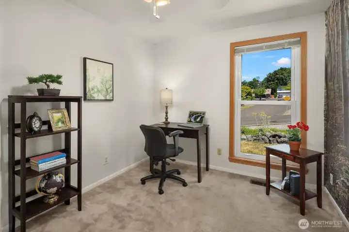 A flexible bedroom currently arranged as a home office, with abundant natural light and enough space to accommodate both work and guest needs.