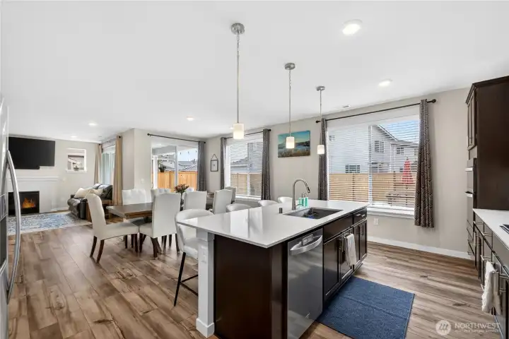 The chef's kitchen features a large center island, quartz countertops, cabinet lighting and built in blue tooth speakers