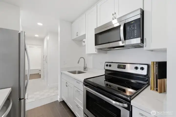 Kitchen showing range, microwave and sink from other direction