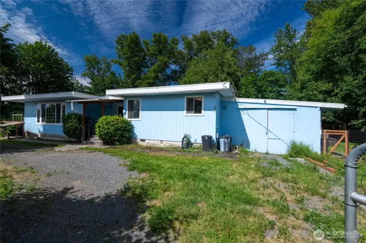 Front of home. Gated circular driveway.  Garage/shop/storage on the right side with outbuildings for additional storage in the backyard.