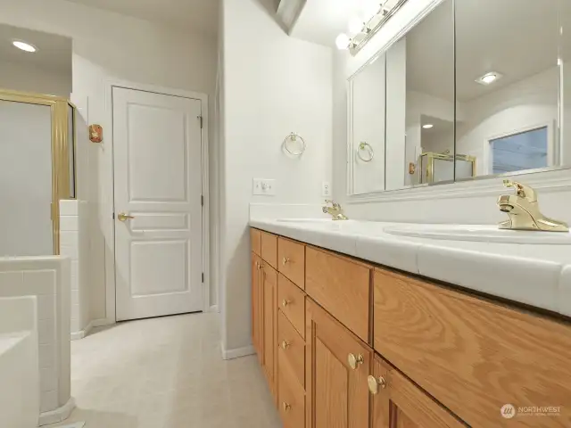 The primary bathroom contains dual vanities, a large tub, shower, separate toilet room, and a large walk-in closet.  Behind the door in the photo is a storage/linen closet.