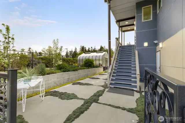 Garden paths wind past raised beds and a stylish greenhouse, perfect for cultivating flowers or fresh produce year-round.
