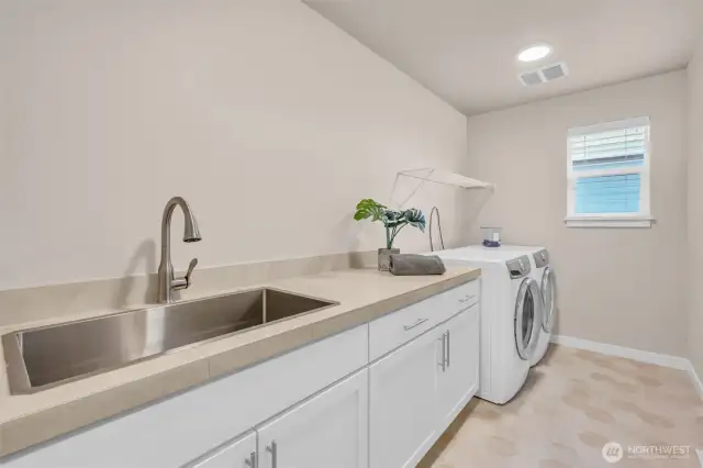Large galley-style landry room with sink and foling area.