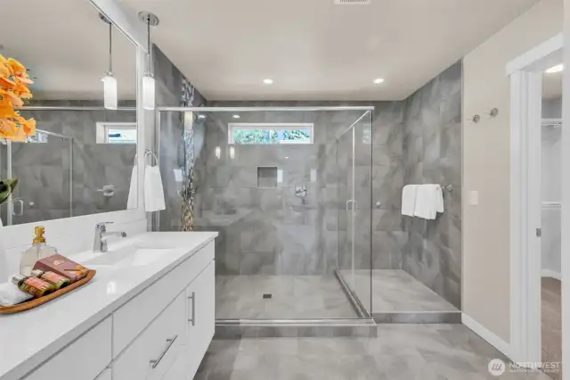 Spa-like ensuite off primary bedroom with double sinks, large walk in shower, water closet for toilet, and large walk-in closet.