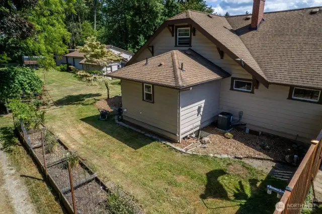 Side yard with garden bed and more space to roam. Yard includes a peach, apple and plum tree, blueberries, rhubarb, grapes, yellow roses and more.