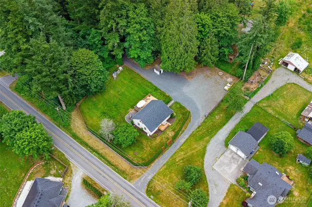 Aerial view showcasing the expansive, private lot surrounded by mature trees—offering ample space, a circular driveway, and secluded charm just minutes from town amenities.