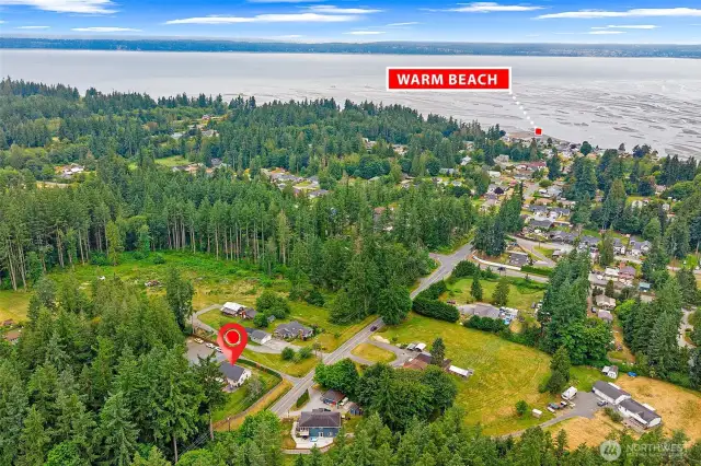 Aerial perspective highlighting the property’s prime location just minutes from Warm Beach—enjoy coastal living with a peaceful, wooded setting and easy access to community amenities.
