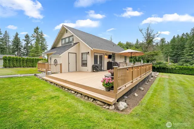 Stunning deck offers the perfect outdoor retreat—complete with space for dining, lounging, and entertaining—set against a backdrop of manicured lawn and mature trees