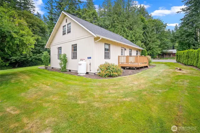 Immaculate side yard with manicured lawn, privacy landscaping, and a secondary deck entrance—offering quiet outdoor space and easy access around the home.