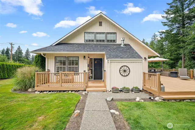 Inviting front entry welcomes you with charming curb appeal, a covered porch, and beautifully landscaped pathways—leading to an expansive deck perfect for outdoor living.