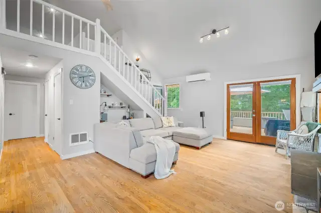 Bright and airy living room with vaulted ceilings, hardwood floors, and French doors leading to the deck—perfectly blending indoor comfort with outdoor charm.