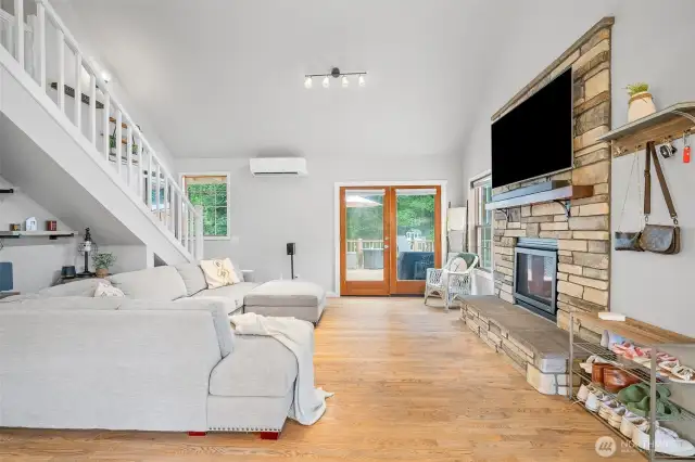 Cozy yet modern living area featuring a stunning stone fireplace with wood mantel, hardwood floors, and access to the deck—perfect for relaxing or entertaining year-round.