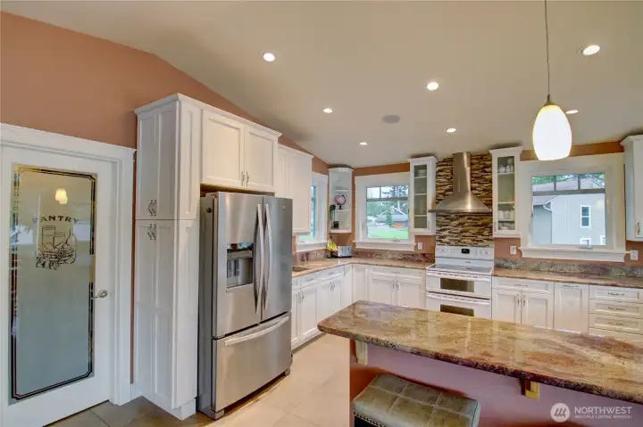 Custom soft close cabinetry with pull-out shelving. There is a bar sink on the back counter for easy access and large walk in pantry with ample storage space.