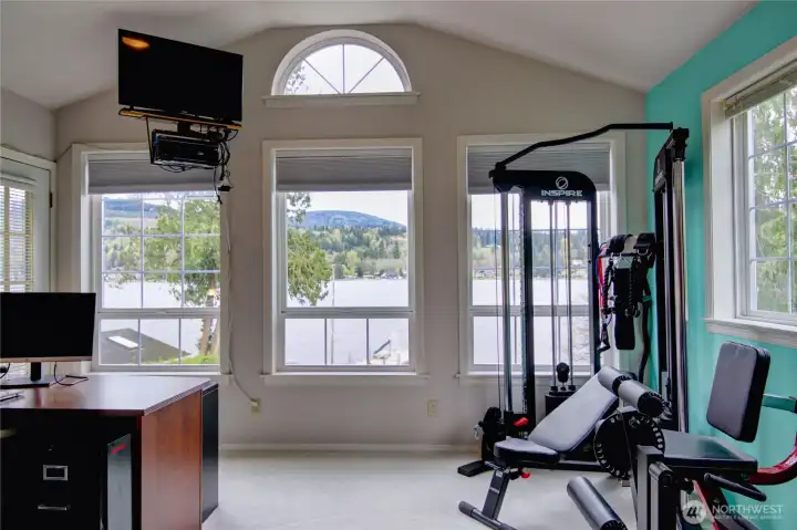 The primeary bedroom has an adjoining flexible space perfect for an office, gym or den perfect for enjoying the views. Door opens to deck over looking the lake. The perfect place to enjoy a morning or evening sip..