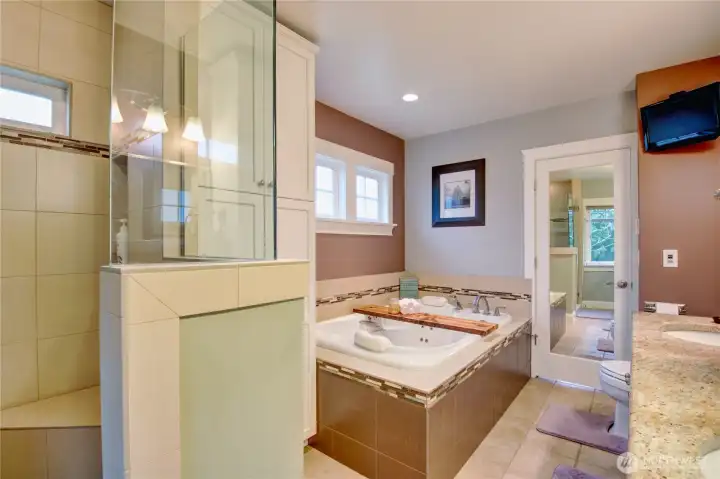 The primary bathroom offers a spa-like experience with heated tile floors, a walk-in shower, and an oversized jacuzzi