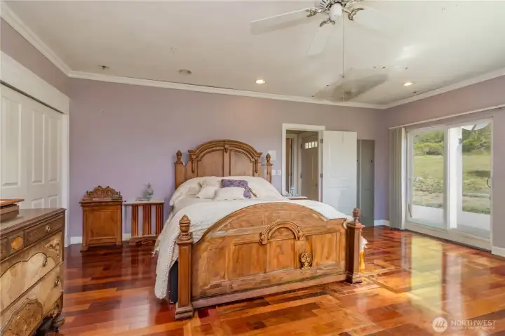 Another view of the main-floor primary suite, with glass sliding doors that open to the great outdoors of the property.
