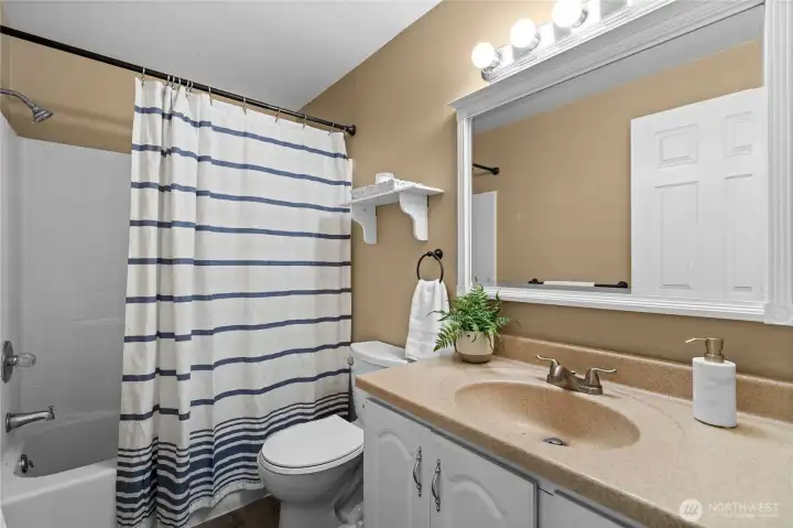 This shared full bathroom balances modern style with everyday functionality, offering plenty of counter space and a classic tub/shower combo to easily serve guests and family alike.