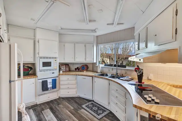 Circular style kitchen has butcher block style counter tops. Plenty of prep and storage space. Ample cabinets and drawers for all your cooking necessities.Garden window view from the double, stainless steel sink with upgraded faucet.