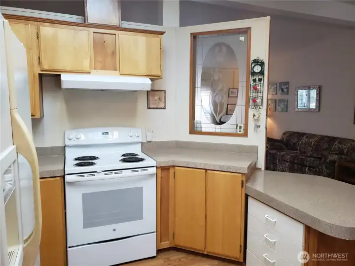 Anther View of the Nice Well Kept U Shaped Kitchen with Newer Appliances, Counter Tops, Laminate Flooring Showing Cathedral Ceilings and a Breakfast Eating Bar.