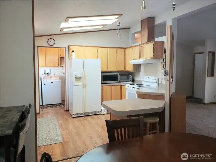 Another View of the Nice Well Kept U Shaped Kitchen with Newer Appliances, Counter Tops, Laminate Flooring Showing Cathedral Ceilings and a Breakfast Eating Bar from the Dining Room.