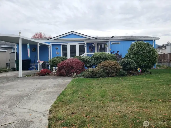 Another Front Picture Showing a Big Yard with Easy Care Landscaping and Carport and Parking Enough for 3 Vehicles.
