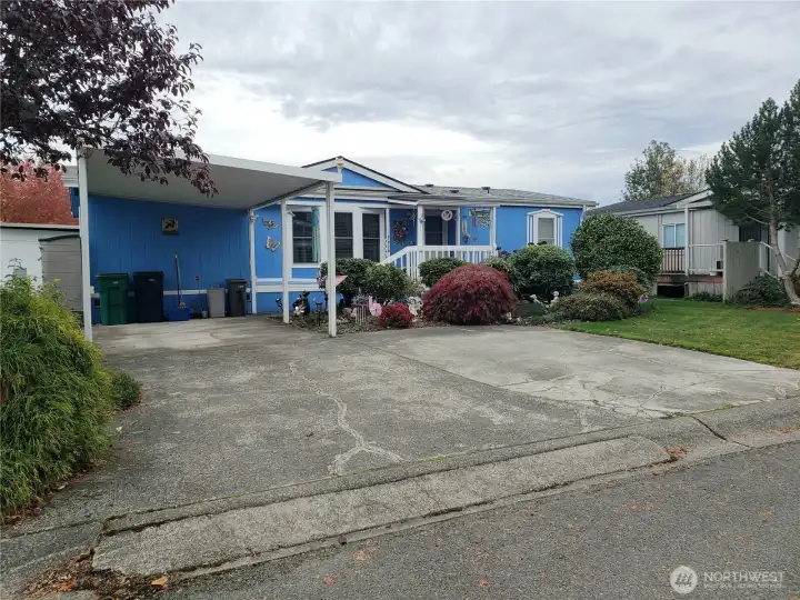 Another Front Picture Showing a Big Yard with Easy Care Landscaping and Carport and Parking Enough for 3 Vehicles.