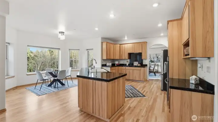 Spacious kitchen with a large center island, surrounded by hardwood floors and beautiful granite countertops