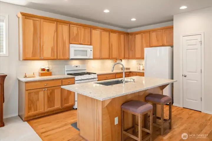 Bright, modern kitchen featuring quartz countertops, stylish backsplash, Blanco sink, and newer appliances (including 2023 range).