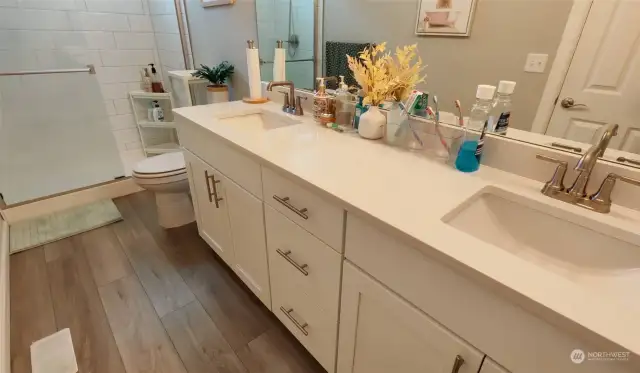 Primary bath with quartz counters, double sinks and tile surround in shower.