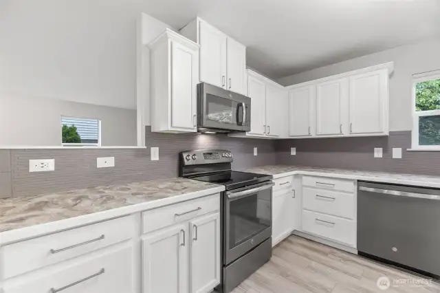Plenty of counter and cabinet space in this sunny, bright kitchen. Updated stainless appliances. Full height tile backsplash, handsome, modern hardware bring it all together.