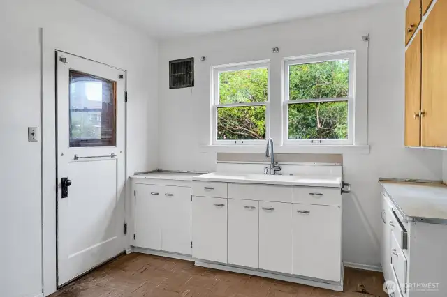 The kitchen has a door that leads downstairs.