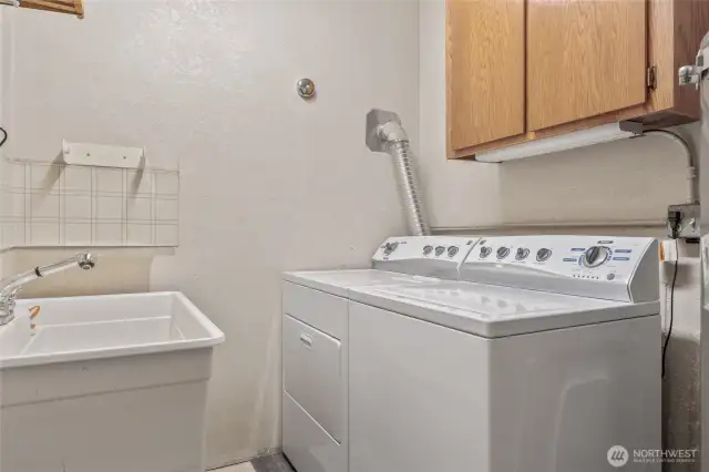 Lower level laundry with basin and storage cabinets.
