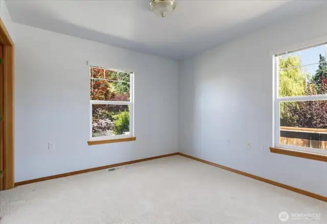 In the guest bedroom, two windows perfectly frame the lush beauty of the trees just beyond, inviting nature’s calm right inside.