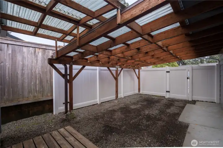 Covered side yard on right of driveway in backyard. Perfect for gardening station, crafts, woodworking, and so much more. Easy access from door in garage.